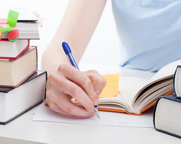 a person writing something on a paper using a pen