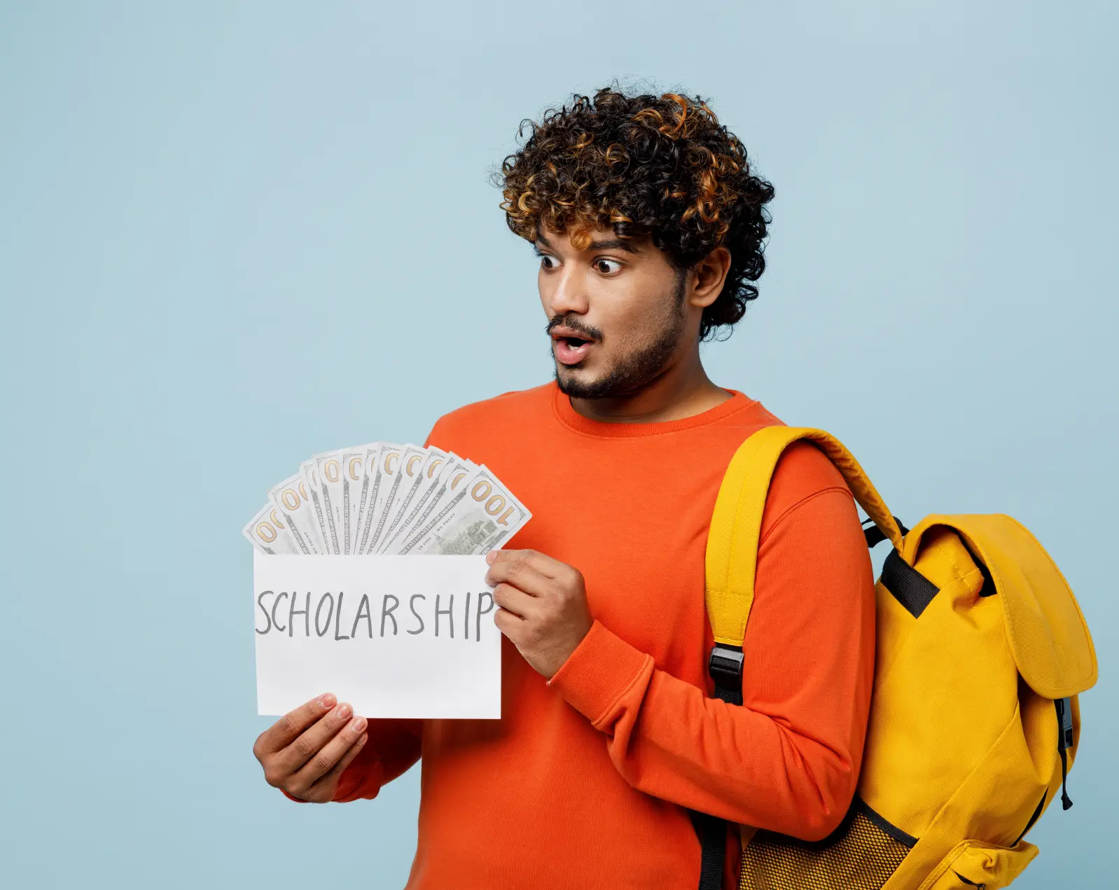 A male student holding scholarship money