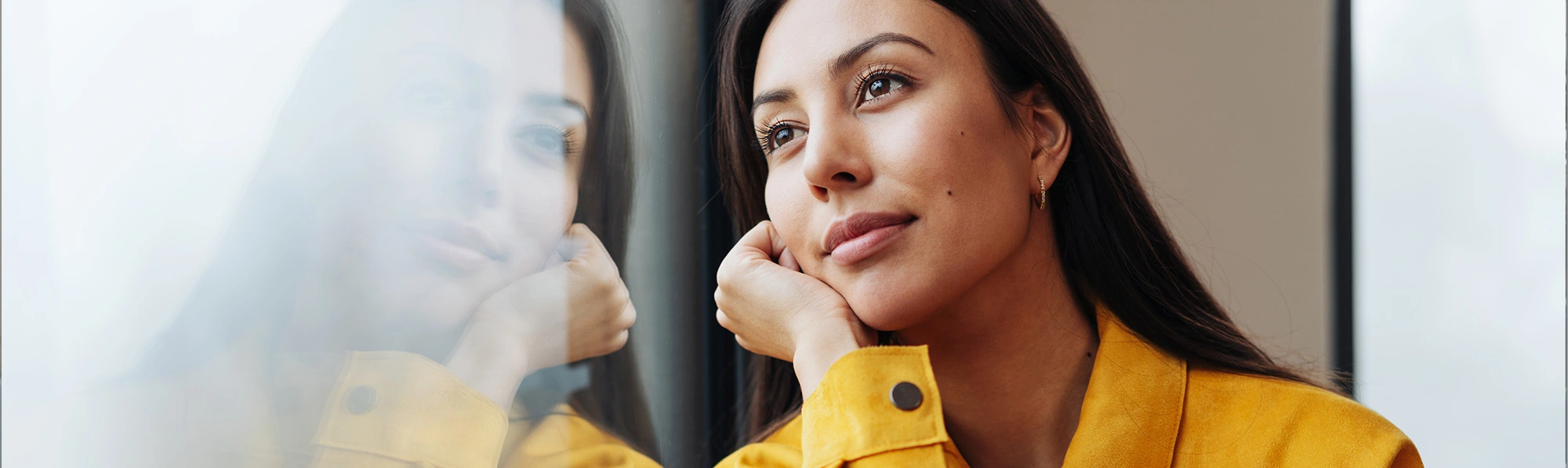 a female student sitting near a glass wall and thinking